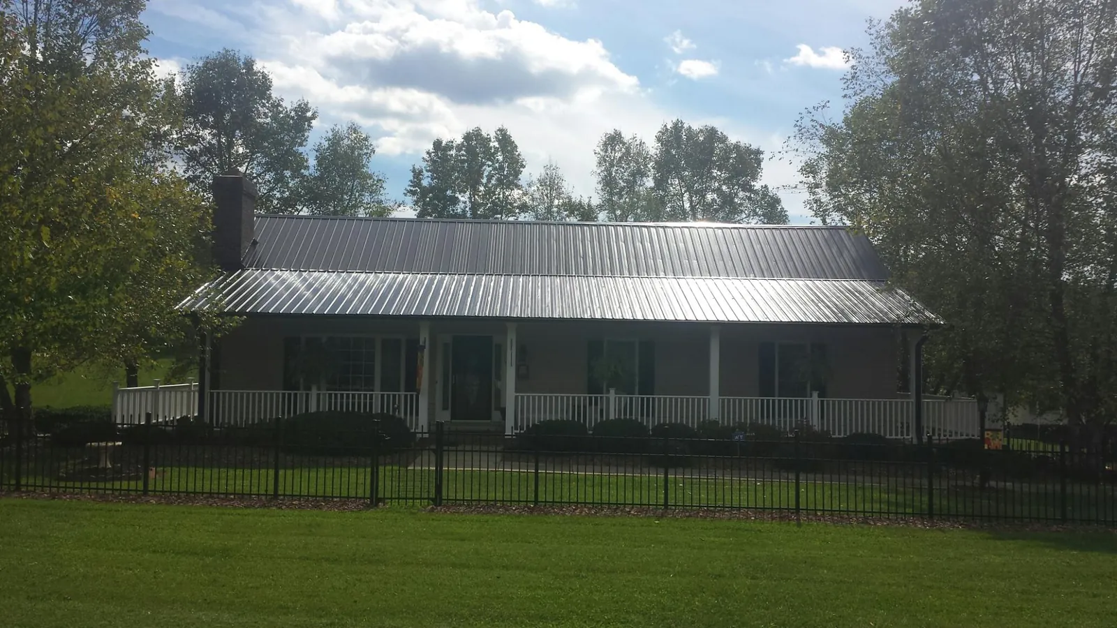 Gray metal roof on a brick ranch with a full width front porch — Gutter Guard Installation work by our crew in Hartsville