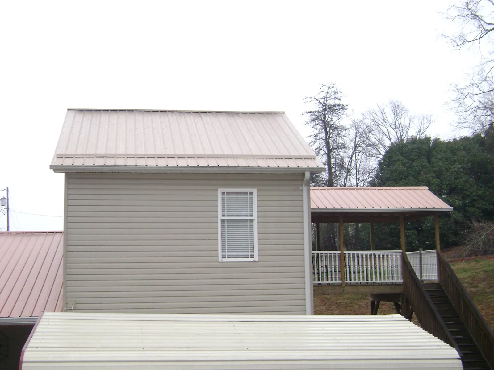 Tan metal roofs on a two story addition and attached porch, from a Roof Replacement job in Hartsville