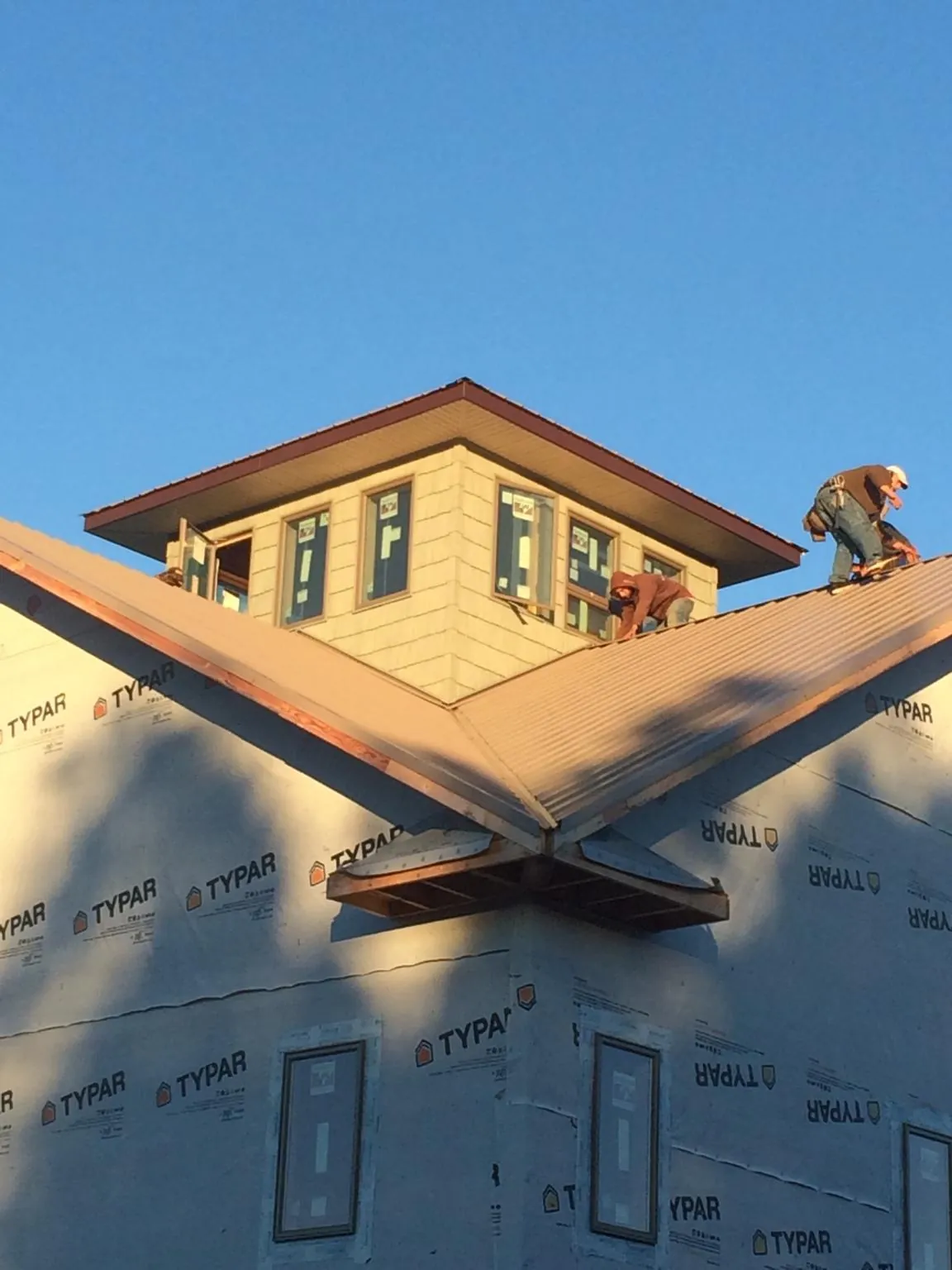 Roofers working around a rooftop cupola on a new metal roof at sunset — Roof Waterproofing in Hartsville by Roofing Brothers